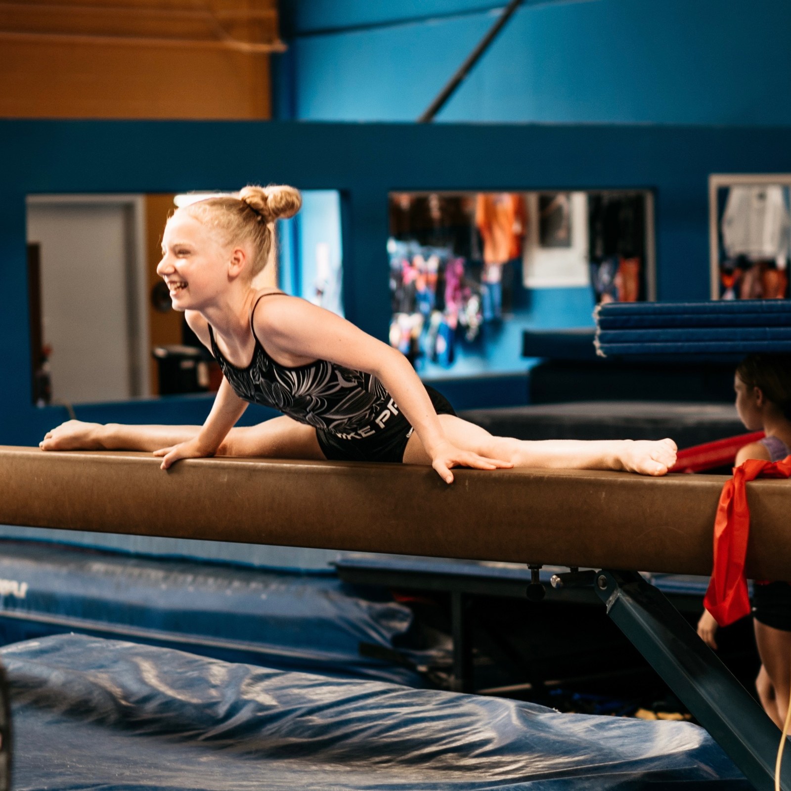 Gymnast smiling while stretching on the balance beam