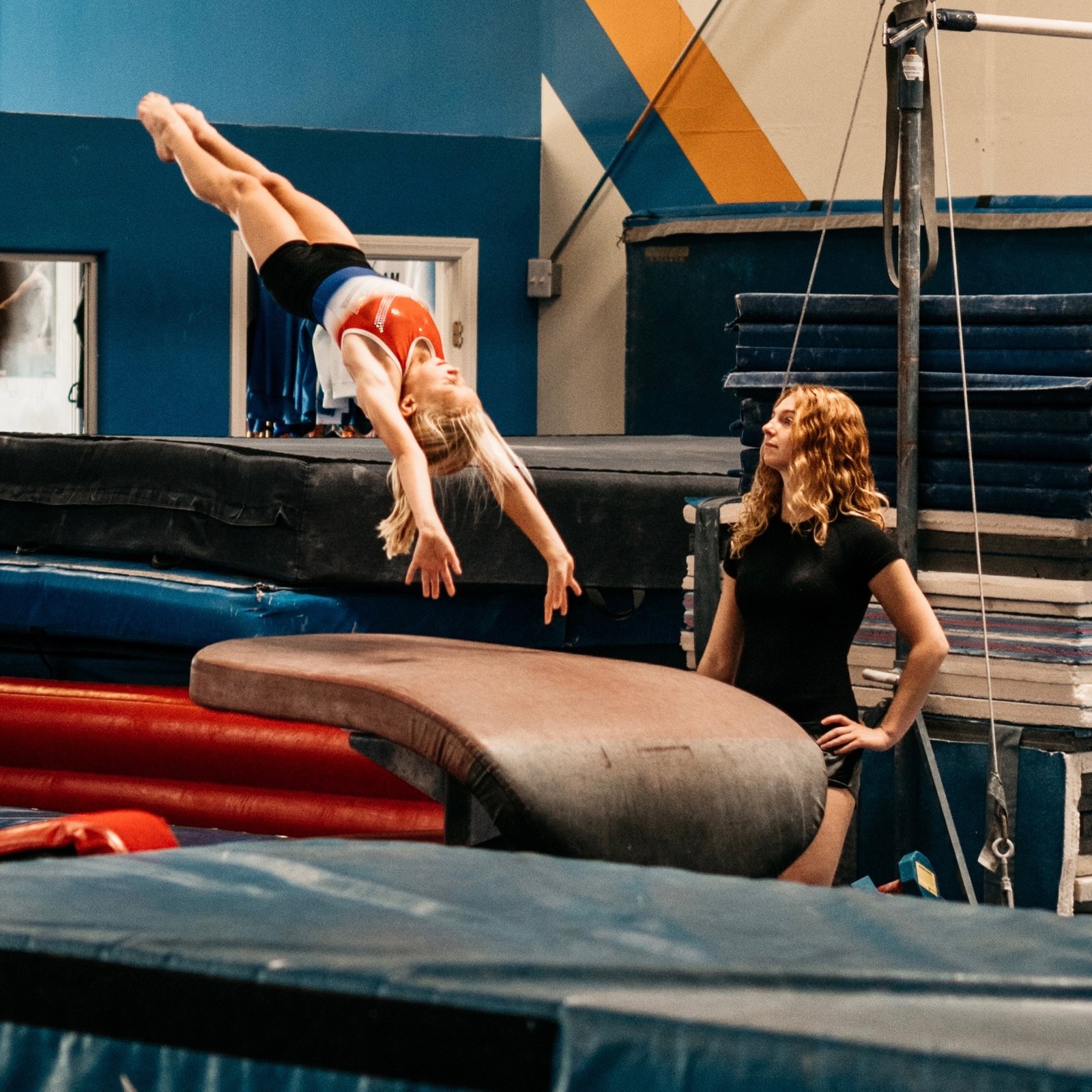 Coach watching a gymnast practice on the vault table
