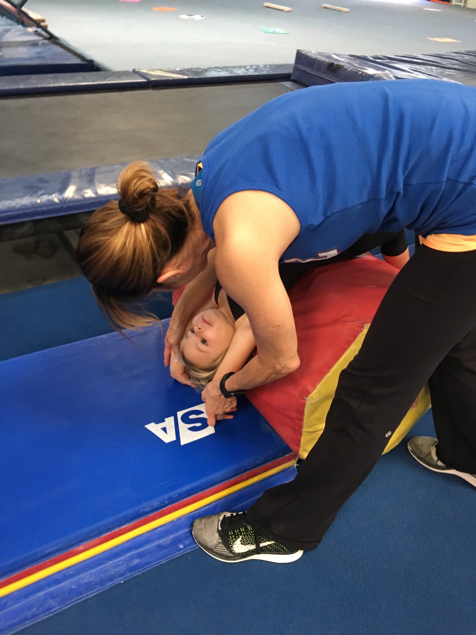 A young child practicing gymnastics with adult support in Parent & Me