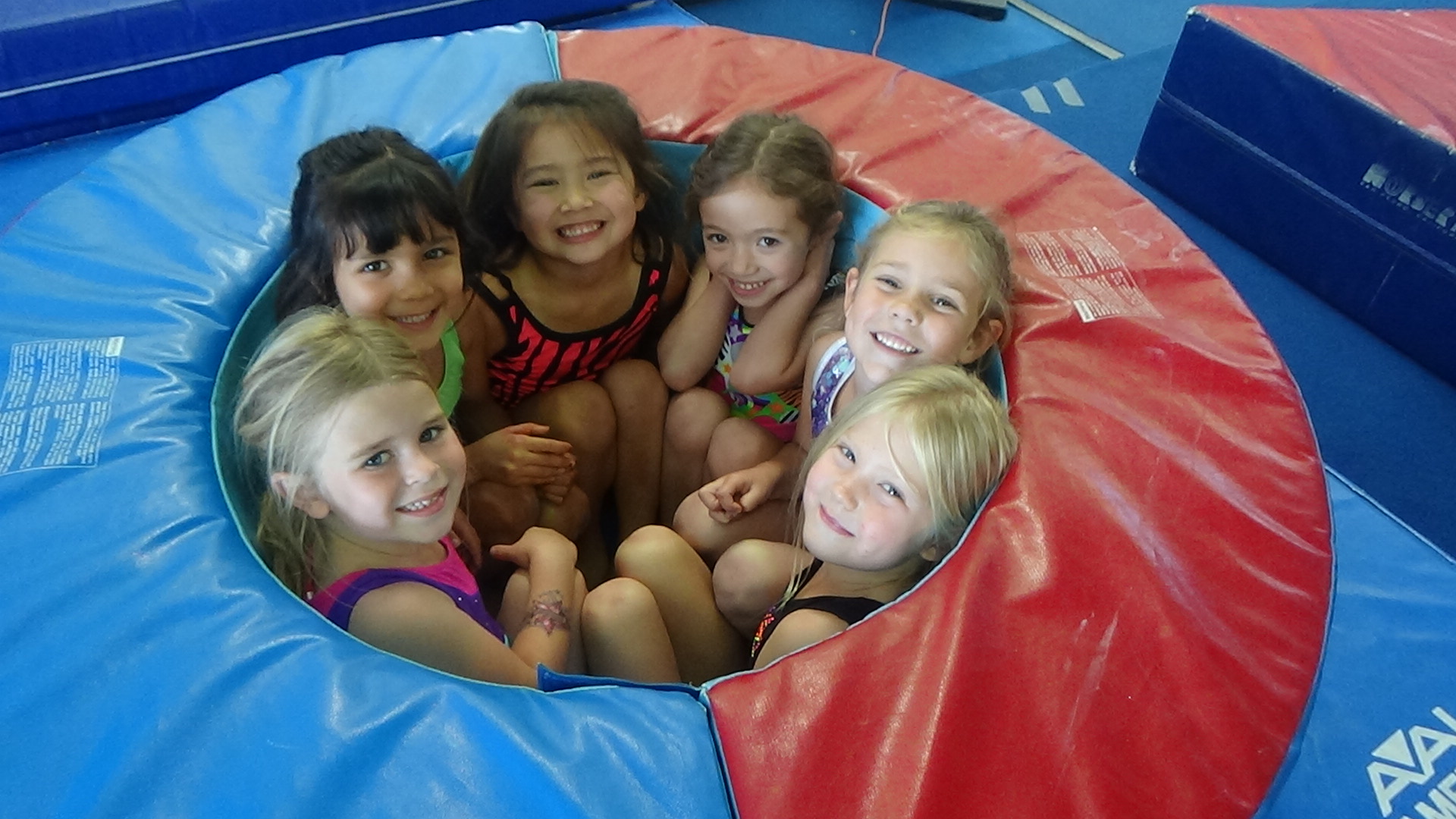 Six preschool gymnasts smiling together at SoCal Gymnastics